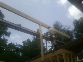 Carpenter setting a ridge beam over a new addition frame — Ice Dam Removal by Roofing Brothers in Newington