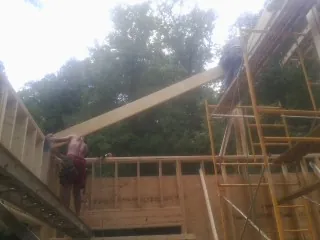 Carpenter raising a rafter beam on a new second story frame in Newington