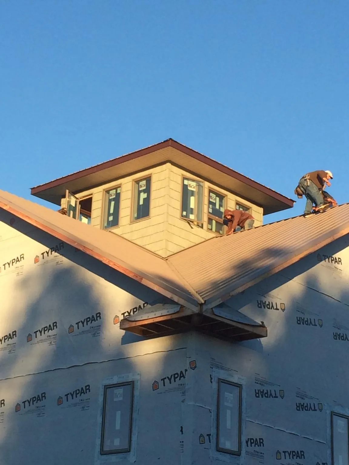 Roofers working around a rooftop cupola on a new metal roof at sunset — Roof Waterproofing in Newington by Roofing Brothers